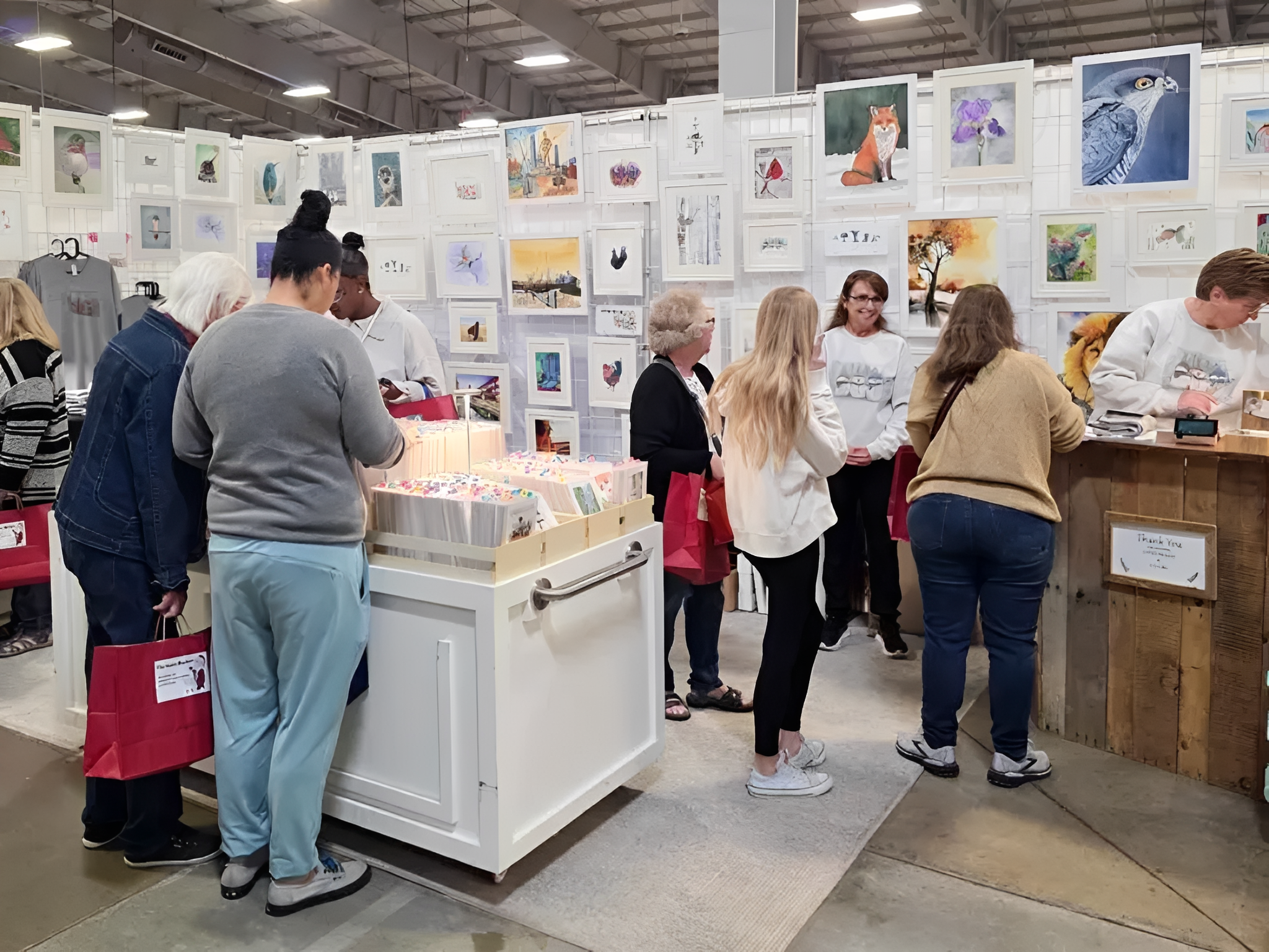 People browsing art prints at indoor craft fair