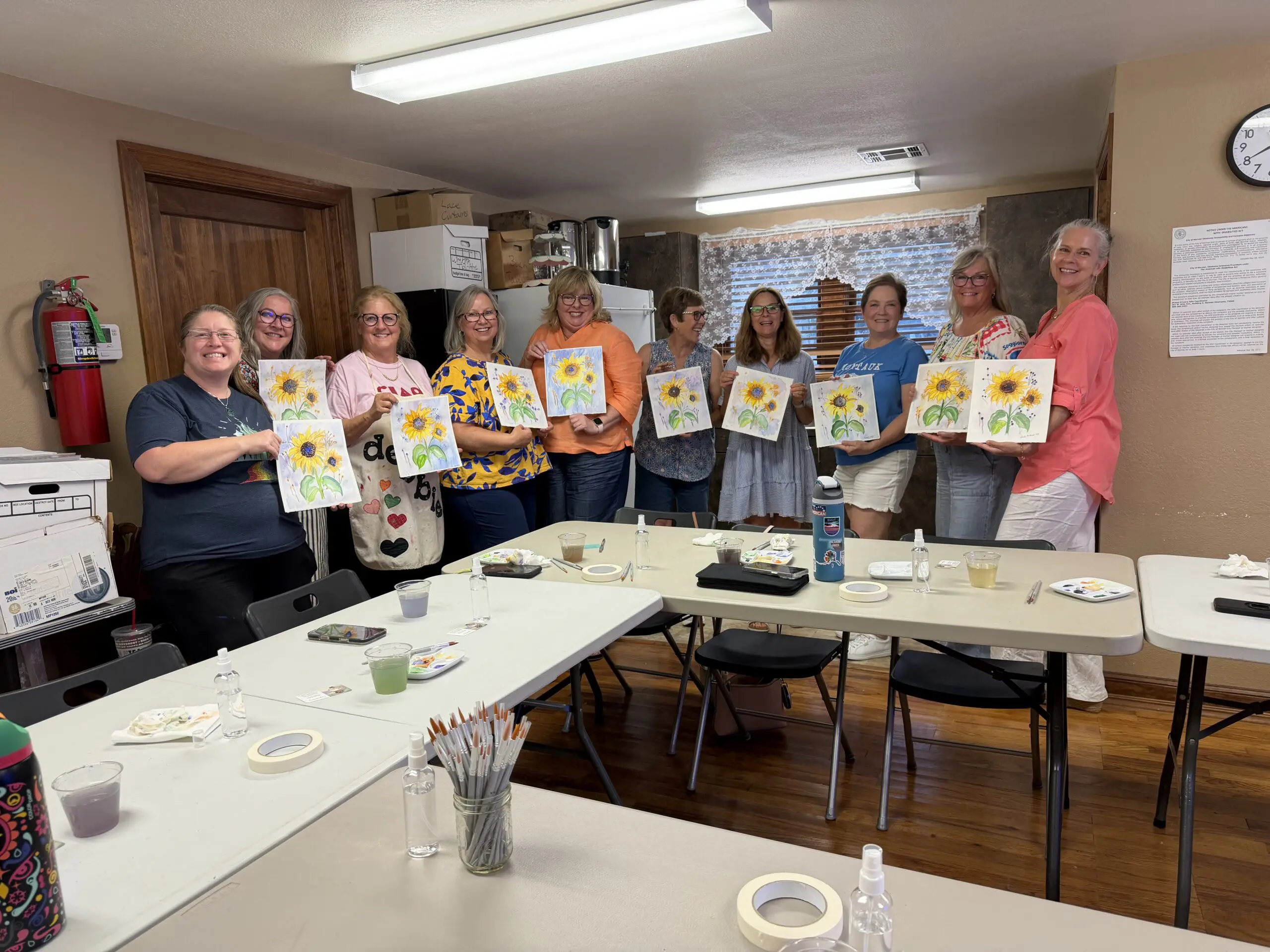 Group of women holding sunflower paintings