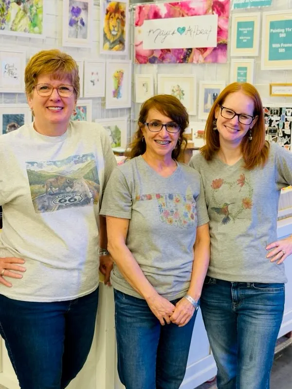 Three smiling women posing in art shop
