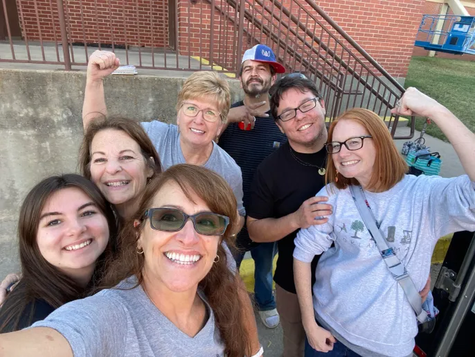 Smiling group selfie outside brick building