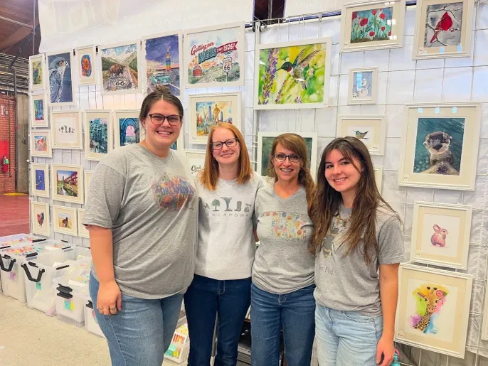 Four people smiling at art fair booth