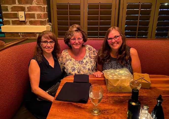 Three people smiling at a restaurant table