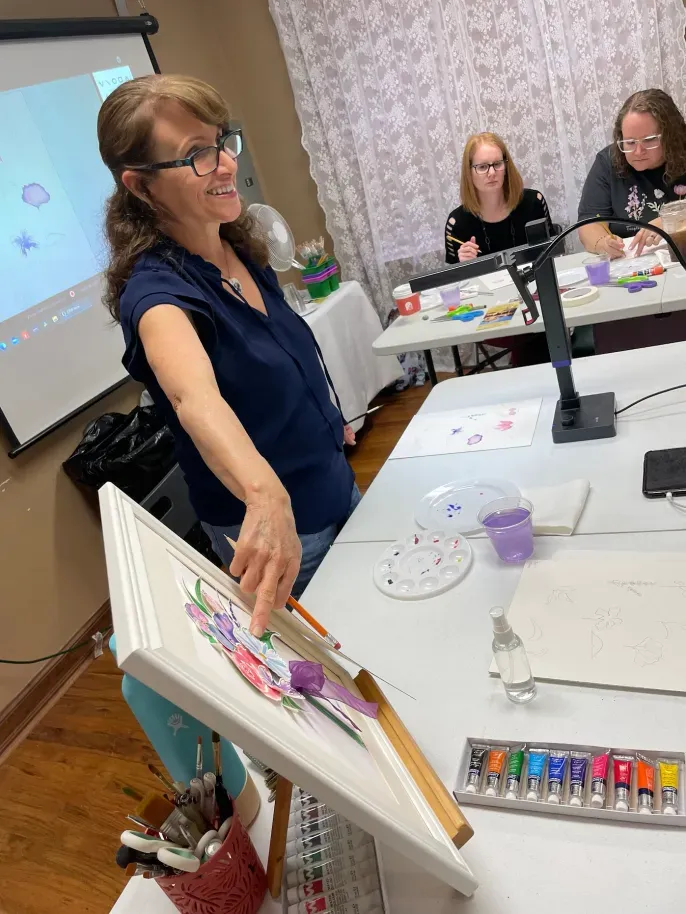 Art instructor teaching painting class with students