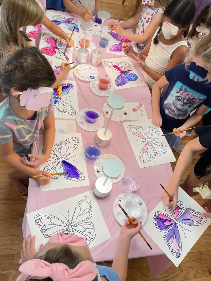 Children painting butterfly watercolor crafts at table