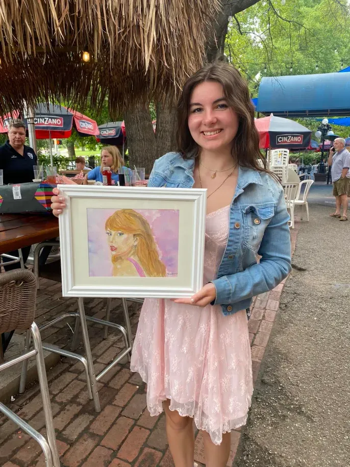 Smiling woman holding framed portrait painting outdoors
