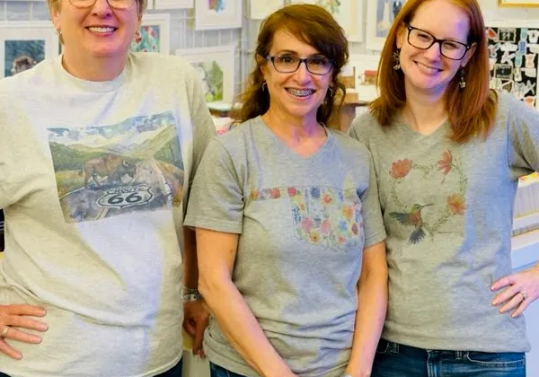 Three smiling women posing in art shop
