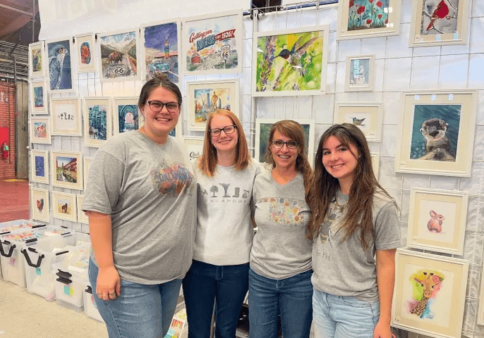 Four people smiling at art fair booth