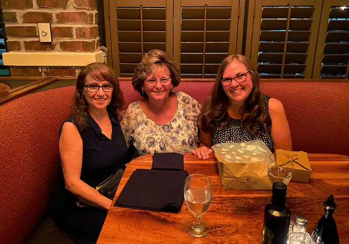 Three people smiling at a restaurant table